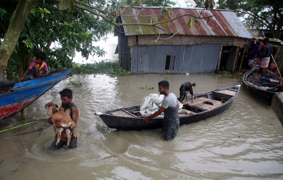 Photo shows people with boat struggling in floodwaters in a village at Louhajang upazila in Munshiganj, Bangladesh, on July 29, 2020. Source: Getty