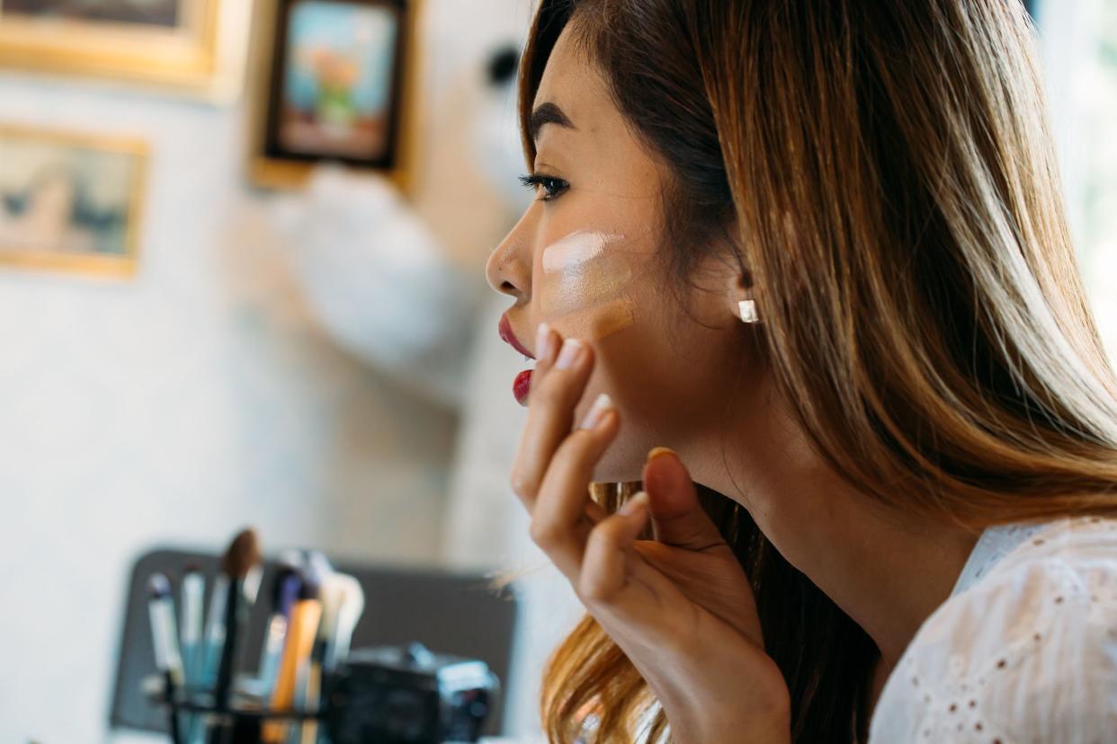 attractive woman testing concealer on face