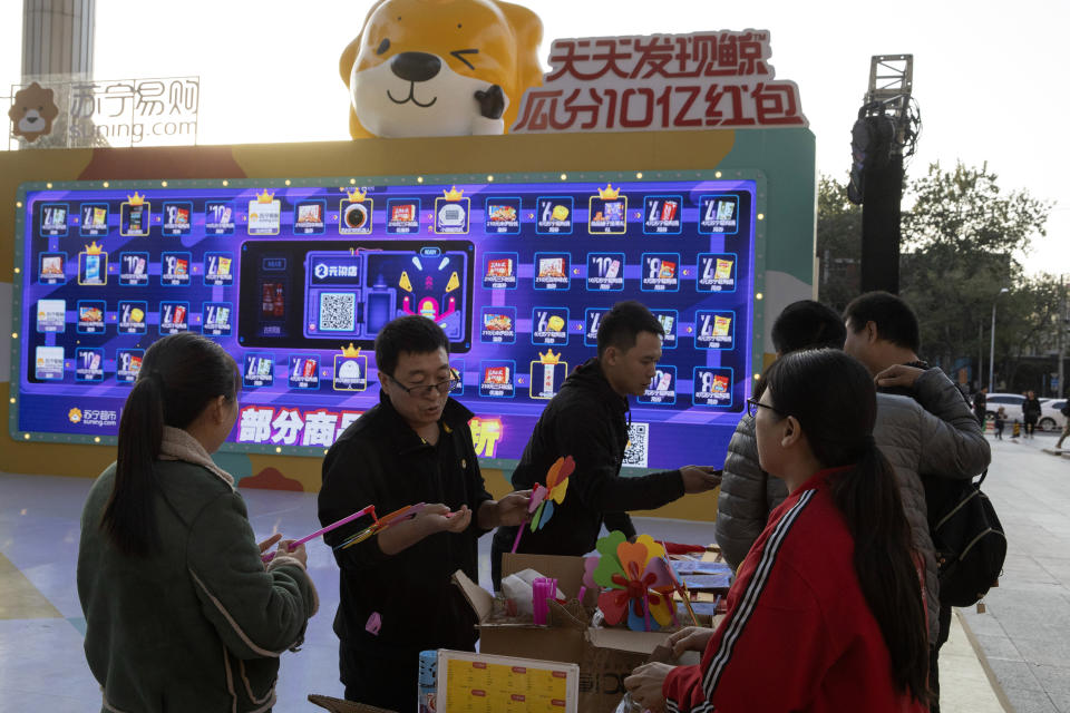 In this photo taken Sunday, Nov. 10, 2019, promoters hand out free gifts as part of a game to promote Nov. 11 Singles day in Beijing. Chinese online shoppers hunt bargains on Singles Day, a holiday invented in the 1990s that has become the world's busiest day for online commerce. (AP Photo/Ng Han Guan)