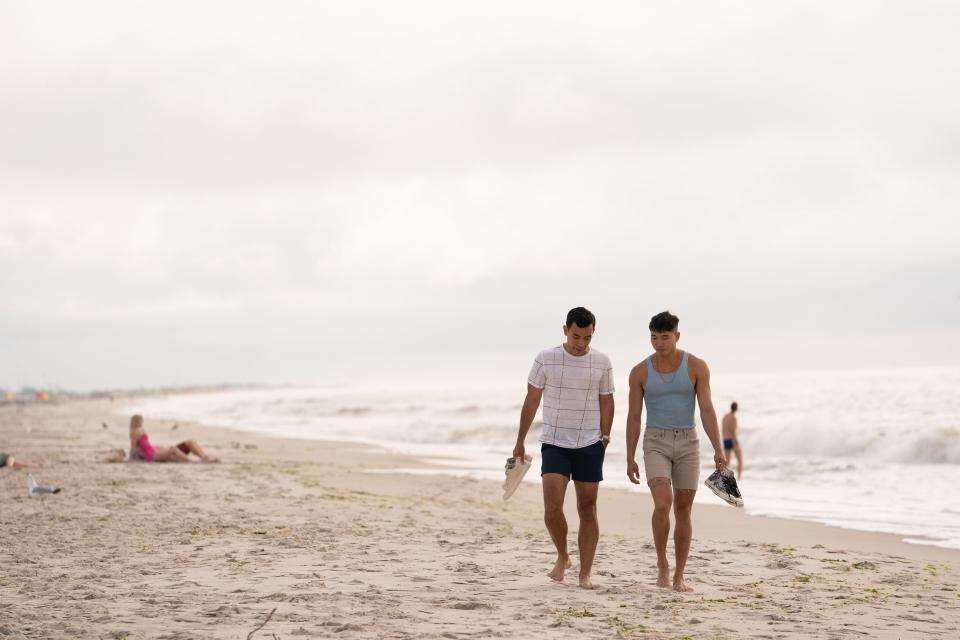 Two individuals walking on a beach with waves in the background