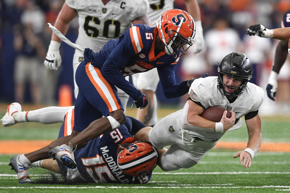 Army quarterback Bryson Daily, right, dives forward as he's tackled by Syracuse linebacker Derek McDonald (15) and defensive back Alijah Clark (5) during the first half of an NCAA college football game in Syracuse, N.Y., Saturday, Sept. 23, 2023. (AP Photo/Adrian Kraus)