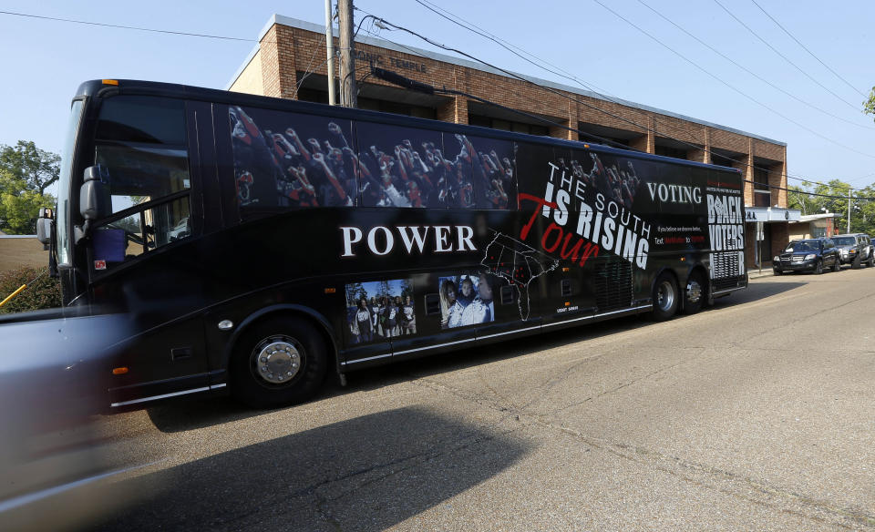 In this Aug. 24, 2018 photo, a truck passes a decorated Black Voters Matter Fund tour bus at a Jackson, Miss., stop where the field team and members of a number of women led Mississippi grassroots political organizations, met to discuss interest and excitement for the upcoming election, documenting the campaigning in locales with important upcoming races where black turnout will be key and exposing traveling national media to their work. (AP Photo/Rogelio V. Solis)
