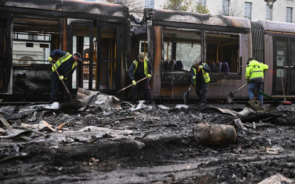 Workers clean up the debris of a burnt tram on Friday morning
