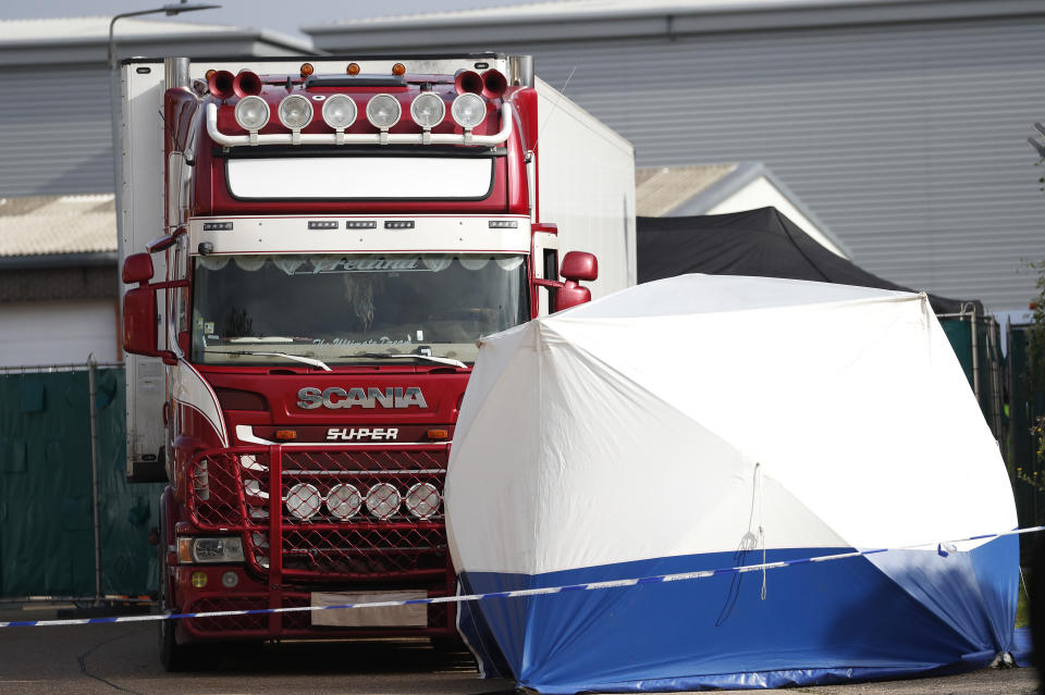 A police forensic tent in front of a truck, in rear, that was found to contain a large number of dead bodies, in Thurrock, South England, early Wednesday Oct. 23, 2019. Police in southeastern England said that 39 people were found dead Wednesday inside a truck container believed to have come from Bulgaria. (AP Photo/Alastair Grant)