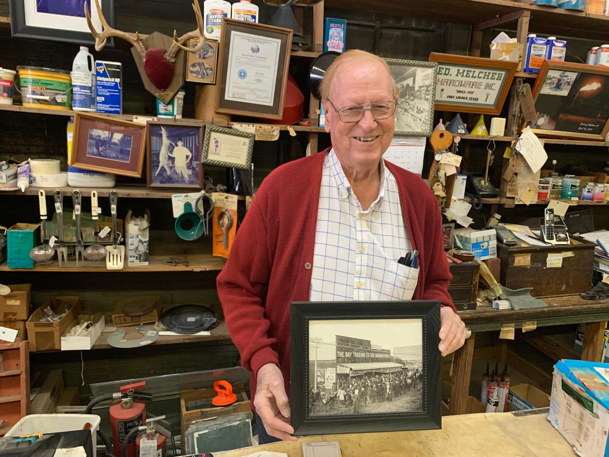 Ed Melcher displays a photograph of the building that houses Melcher's Hardware Store in the days when the streets of downtown Port Lavaca, originally named Lavaca, were crowded with horses and carts. The Melcher family preserves the store as it has looked for some 100 years, and the business still meets locals' hardware needs.
