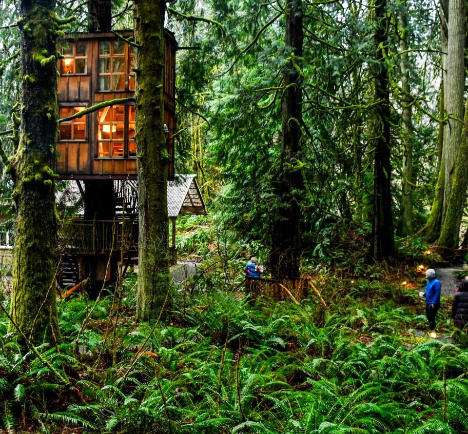 The lights are on in a two-story treehouse in a forest near Seattle.