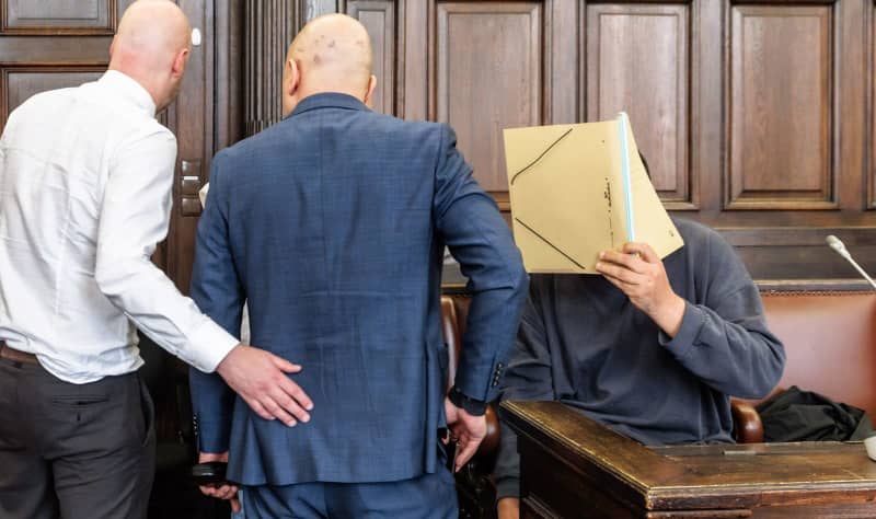 The suspect hides his face in the courtroom.  The Supreme Court trial concerns war crimes committed by a Syrian government militia between 2012 and 2015. The suspect is a 47-year-old Syrian who entered Germany in February 2016 and was arrested in Bremen in August 2023.  Markus Scholz/dpa-Pool/dpa