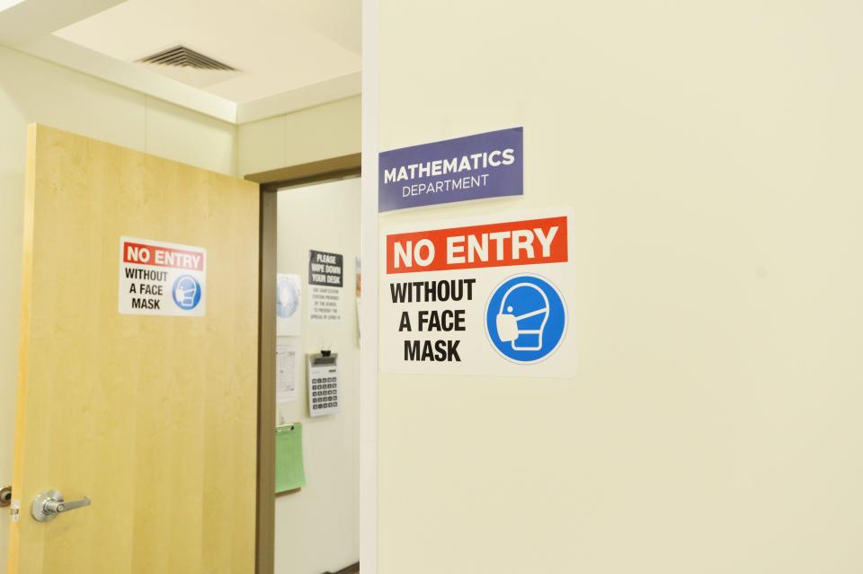 A sign outside a math class at Downtown Burlington High School reminds students to wear a face mask to prevent the spread of COVID-19. Pictured March 4, 2021. The high school resumed classes in the former Macy's department store building.