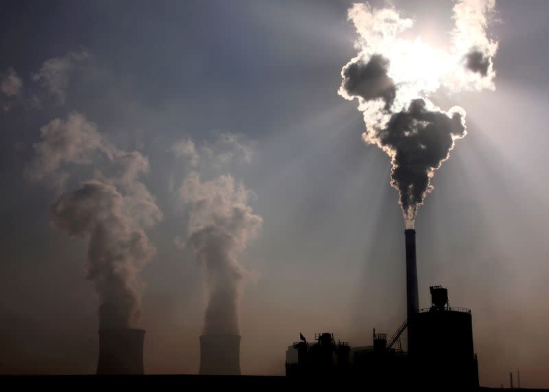 FILE PHOTO: A coal-burning power plant can be seen behind a factory in the city of Baotou, in China's Inner Mongolia Autonomous Region