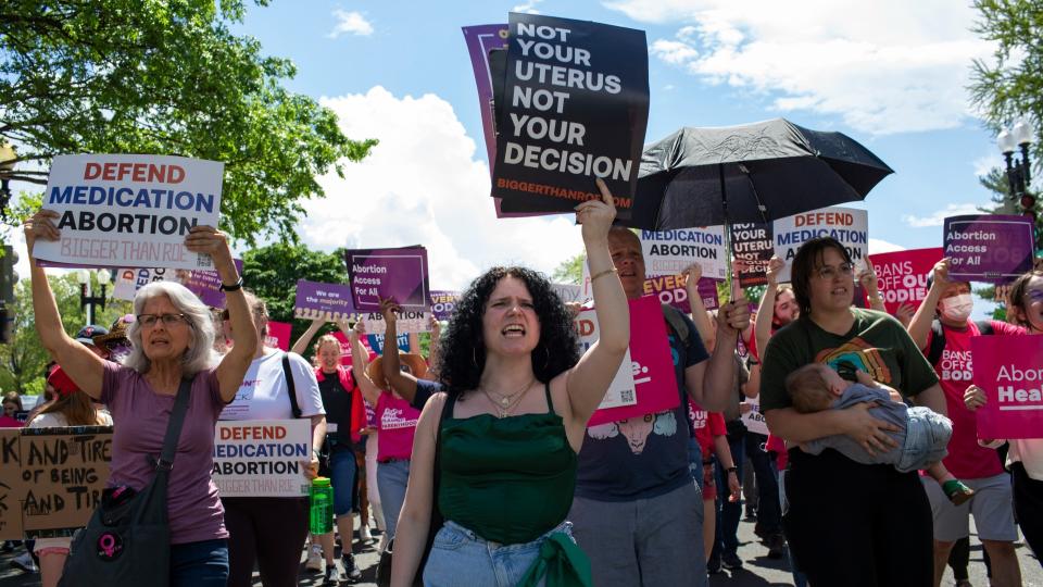 Image of activists taking part in a march in support of abortion rights, some are holding placards up in the air while another carries a child