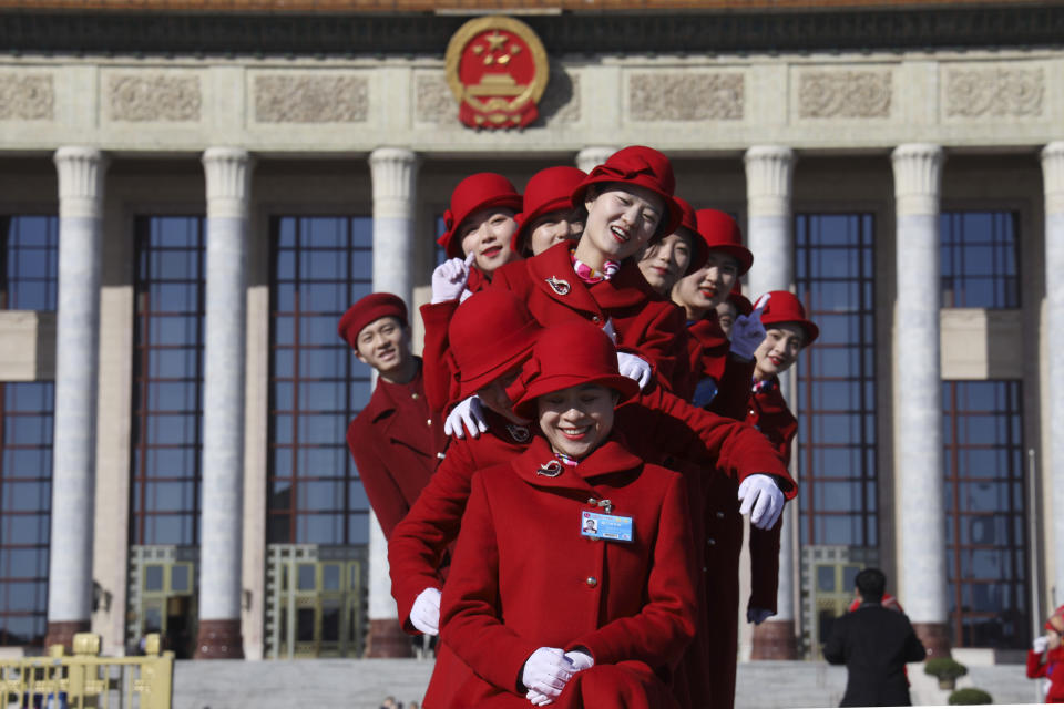 In this March 12, 2019, photo, Chinese bus ushers pose for photos outside the Great Hall of the People during a plenary session of the National People's Congress held in Beijing, China. The country's top judge and head prosecutor delivered reports to the nearly 3,000 members of the ceremonial legislature on their accomplishments over the past year in curbing crime and prosecuting wrong doers, along with their plans for the year ahead. (AP Photo/Ng Han Guan)