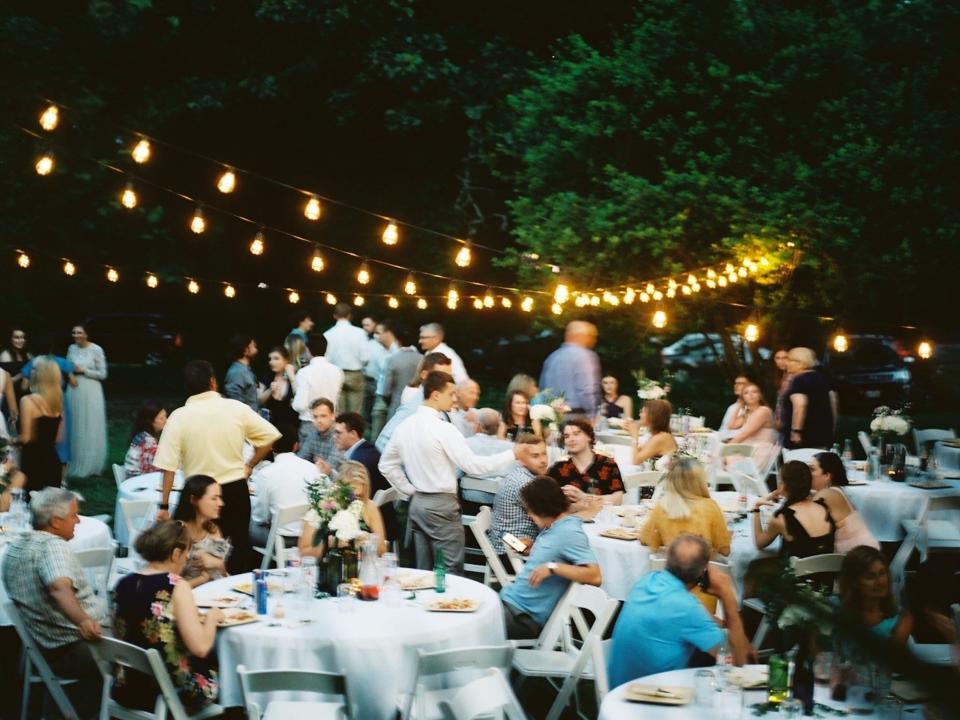 Guests sit at tables in a backyard wedding.