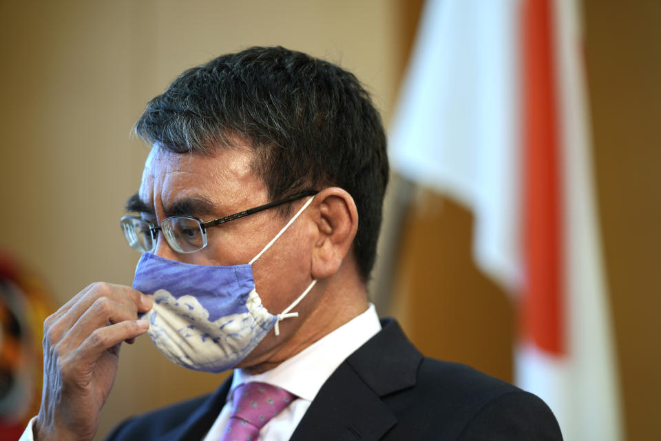 Taro Kono, Japan's minister in charge of a huge vaccination campaign, adjusts his face mask during an interview with The Associated Press at his office in Tokyo Wednesday, July 28, 2021. As Olympics host Tokyo saw another record number of coronavirus cases Wednesday, Kono told that the speed of the inoculation campaign, which is averaging about 10 million shots a week after a late start, is less urgent than getting shots to young people, who are blamed for spreading the virus. (AP Photo/Eugene Hoshiko)