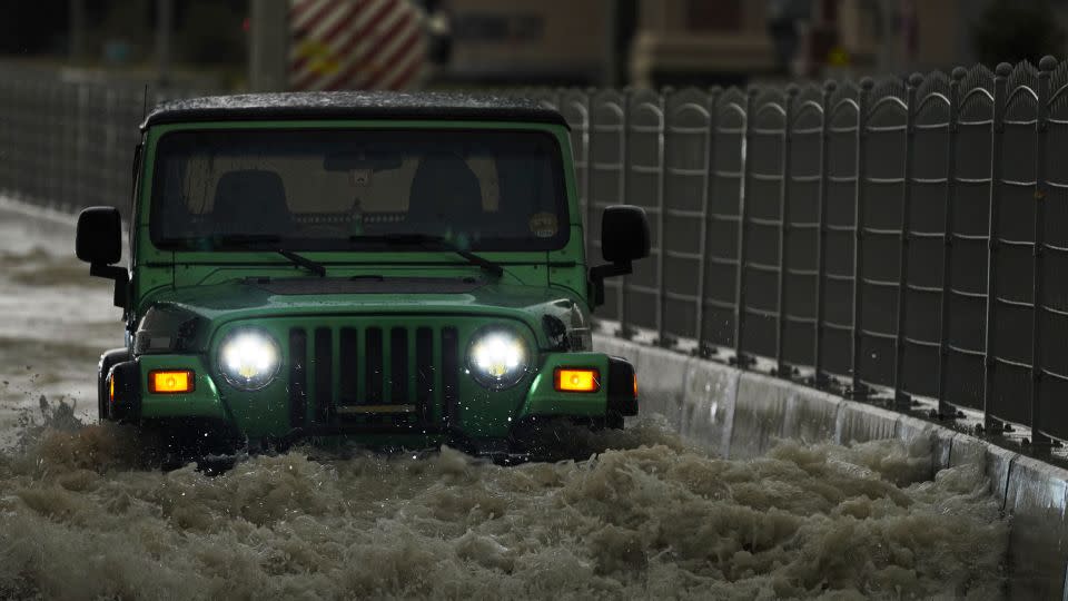 A vehicle drives through deep floodwaters in Dubai, United Arab Emirates, Tuesday. - Jon Gambrell/AP