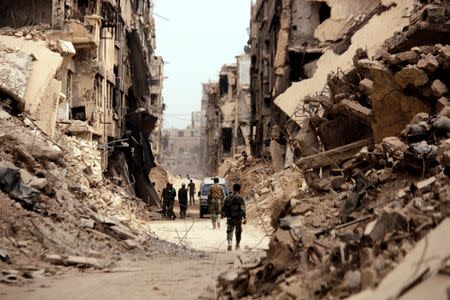 Soldiers walk past damaged buildings in Yarmouk Palestinian camp in Damascus, Syria May 22, 2018. REUTERS/Omar Sanadiki/Files