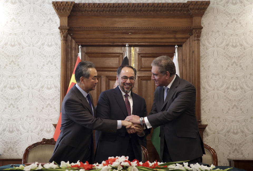 Afghanistan's Minister of Foreign Affairs Salahuddin Rabbani, center, Pakistan's Foreign Minister Shah Mehmood Qureshi, first right, and Chinese Foreign Minister Wang Yi, first left, shake hands after signing the agreement during a meeting at the presidential palace in Kabul, Afghanistan, Saturday, Dec. 15, 2018. Afghanistan, Pakistan and China are meeting in the Afghan capital to discuss trade, development and ending the region's relentless conflicts. (AP Photo/Massoud Hossaini)