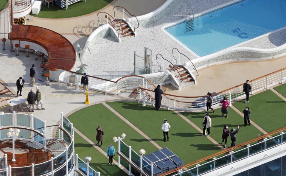 Photo taken from a Kyodo News helicopter shows passengers strolling on the deck of the cruise ship Diamond Princess docked at the port of Yokohama.