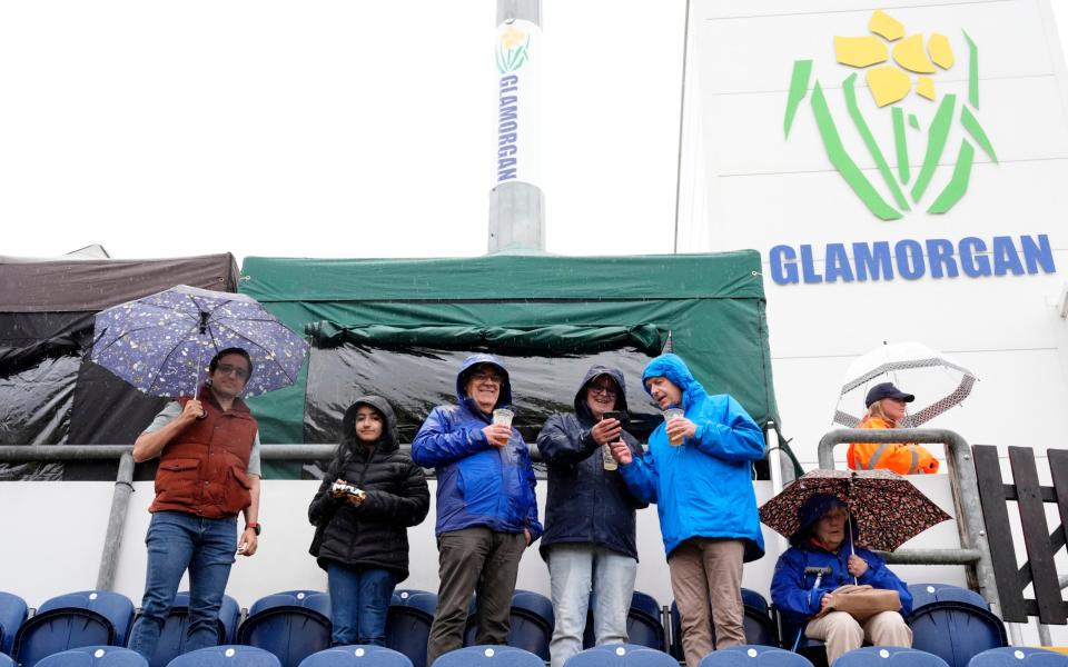 Fans in the stands shelter from the rain