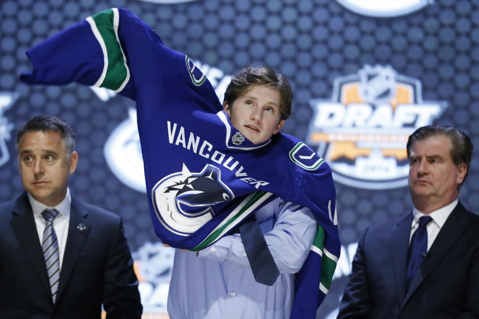 Jared Mccann pulls on a Vancouver Canucks sweater after being chosen 24th overall during the first round of the NHL hockey draft, Friday, June 27, 2014, in Philadelphia. (AP Photo/Matt Slocum)