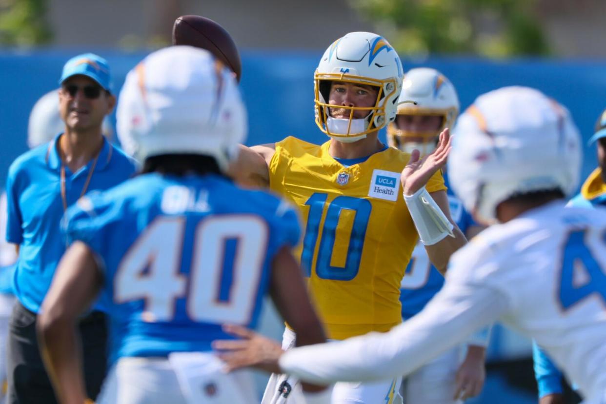 Quarterback Justin Herbert delivers a pass under the watchful eyes of coach Jim Harbaugh during training camp at The Bolt.