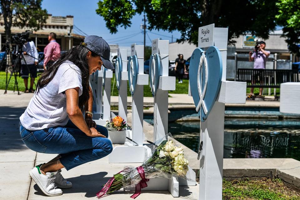 Meghan Markle, the wife of Britain's Prince Harry, places flowers as she mourns at a makeshift memorial outside Uvalde County Courthouse in Uvalde, Texas, on May 26, 2022. - Grief at the massacre of 19 children at the elementary school in Texas spilled into confrontation on May 25, as angry questions mounted over gun control -- and whether this latest tragedy could have been prevented. The tight-knit Latino community of Uvalde on May 24 became the site of the worst school shooting in a decade, committed by a disturbed 18-year-old armed with a legally bought assault rifle.