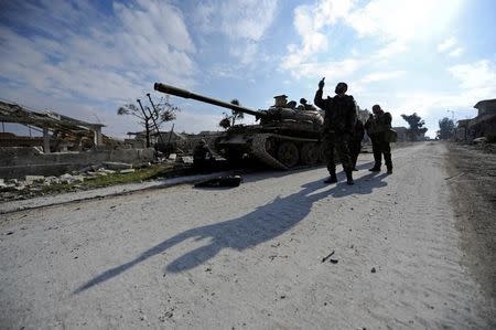 Forces loyal to Syria's President Bashar al-Assad walk past a tank in the government held Sheikh Saeed district of Aleppo, during a media tour, Syria December 12, 2016. REUTERS/Omar Sanadiki