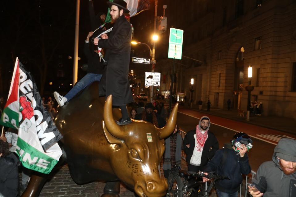 A man is seen dancing on top of the “Charging Bull” statue in New York City while waving a Palestinian flag on Thursday night. William C Lopez/New York Post