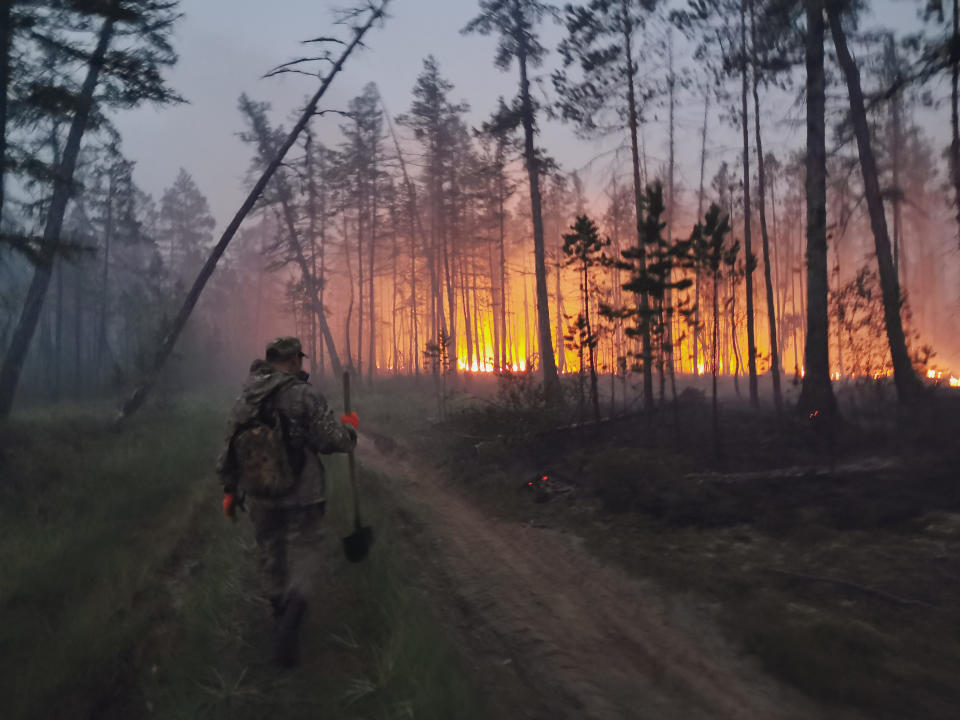 FILE - In this Saturday, July 17, 2021 file photo, a volunteer walks to douse a forest fire in the republic of Sakha also known as Yakutia, Russia Far East. Russia has been plagued by widespread forest fires, blamed on unusually high temperatures and the neglect of fire safety rules, with Sakha-Yakutia in northeastern Siberia being the worst affected region lately.Each year, thousands of wildfires engulf wide swathes of Russia, destroying forests and shrouding broad territories in acrid smoke. This summer has seen particularly massive fires in Yakutia in northeastern Siberia following unprecedented heat. (AP Photo/Ivan Nikiforov, File)