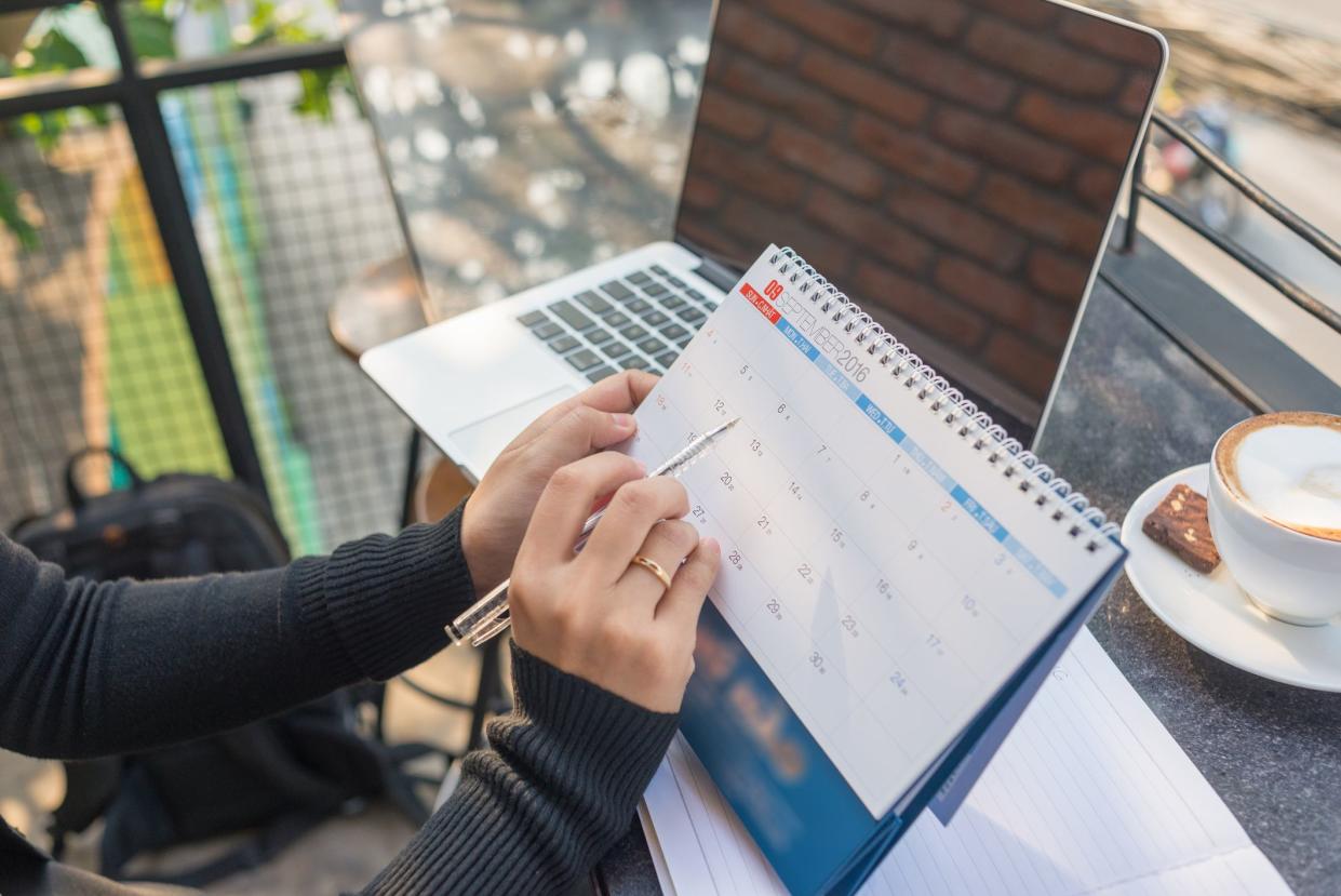 Woman hand carrying calendar and pointing on it by pen