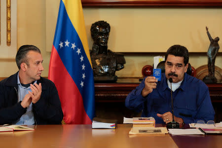 Venezuela's President Nicolas Maduro (R) shows a copy of the country's constitution as he sits next to Vice President Tareck El Aissami, during a meeting with Vice Presidents at Miraflores Palace in Caracas, Venezuela June 1, 2017. Miraflores Palace/Handout via REUTERS