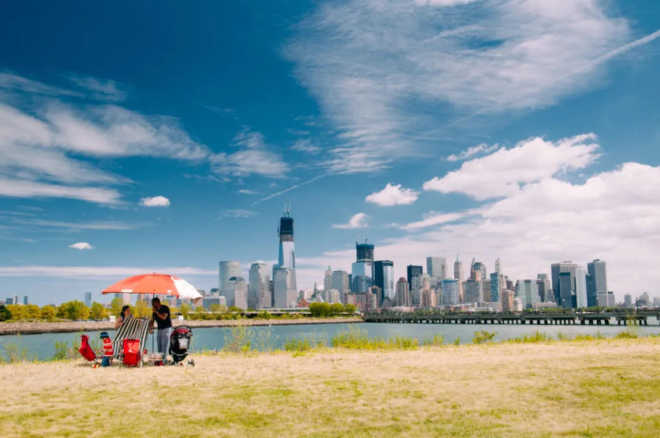 “Jersey City , United States – July 21, 2012: Family setting up the Picnic at Liberty State Park with New York skyline on the horizon.”