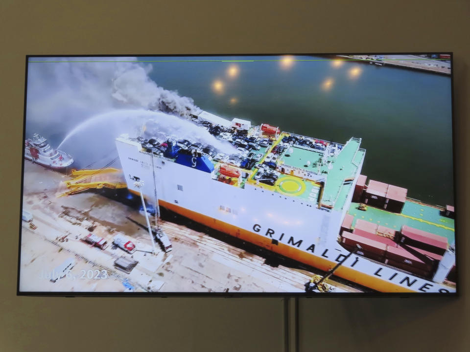 A photo displayed on a video monitor in Union,N.J., Wednesday, Jan. 10, 2024 shows a burning cargo ship in Newark N.J. on July 5, 2023. Federal investigators are conducting hearings into the blaze that killed two Newark, N.J. fire captains. (AP Photo/Wayne Parry)