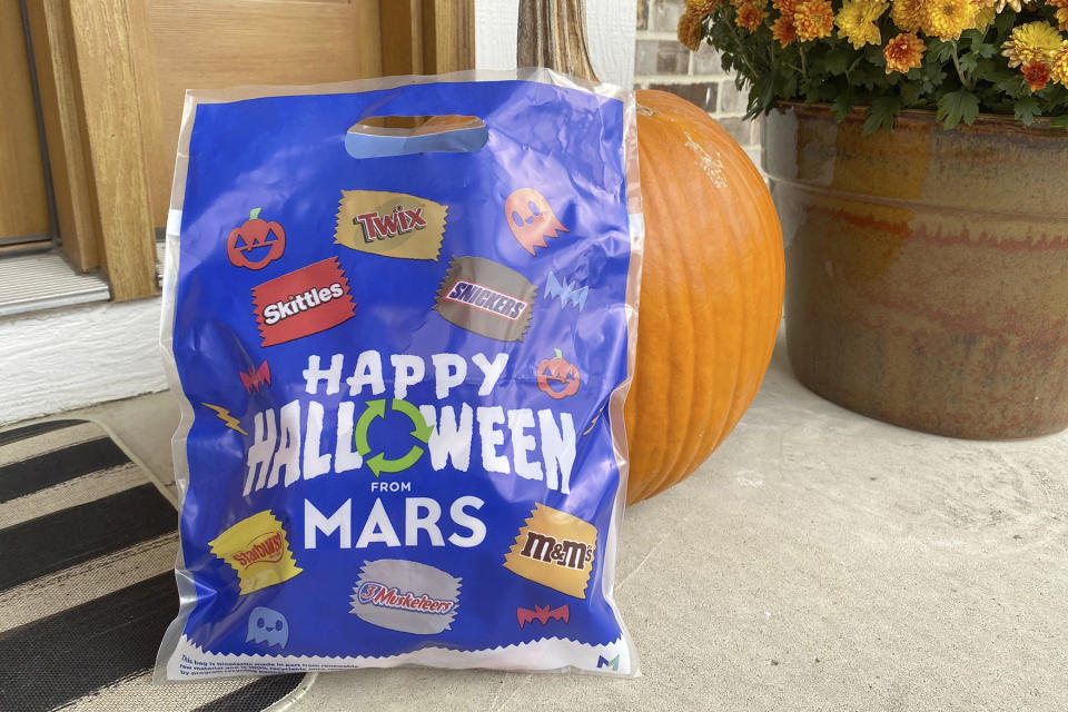 A bag distributed by Mars - the maker of Snickers and M&M's - for recycling candy wrappers is positioned near a pumpkin in Ann Arbor, Mich., on October 19, 2022. The bags can be filled with wrappers and packaging from any brand and mailed free to a specialty recycler in Illinois. (AP Photo/Dee-Ann Durbin)