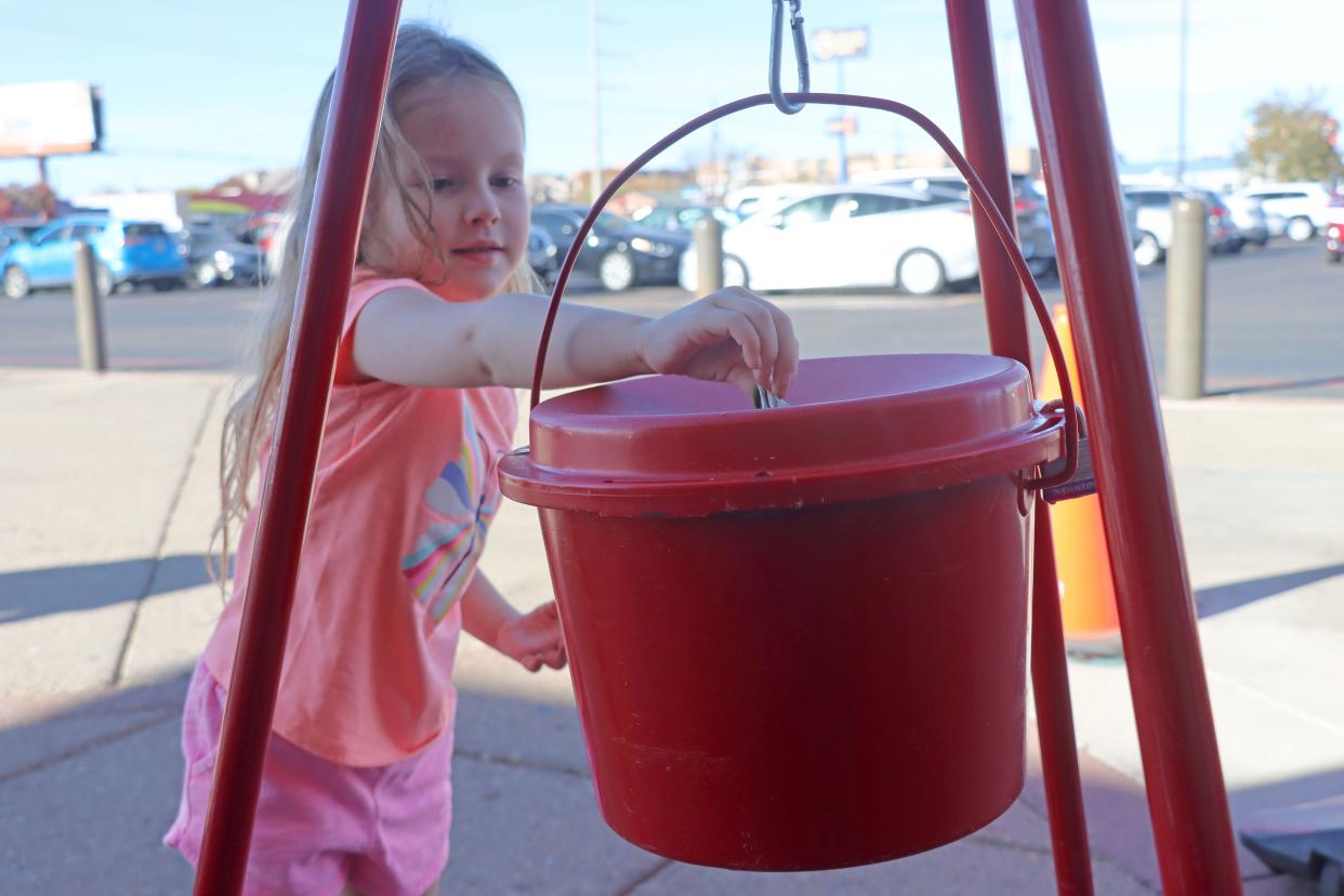 Leia Fulcher puts her money in the Red Kettle for the Salvation Army's annual holiday drive.