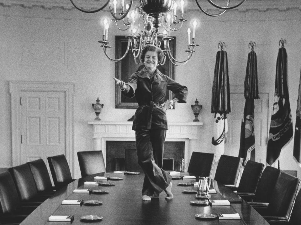 Betty Ford strikes a pose on the Cabinet Room table at the White House wearing pants.