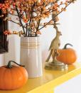 <p>Mini pumpkins and a vase of orange berries pop against a yellow mantel. The happy color scheme hints at candy corn, a favorite fall candy!</p>