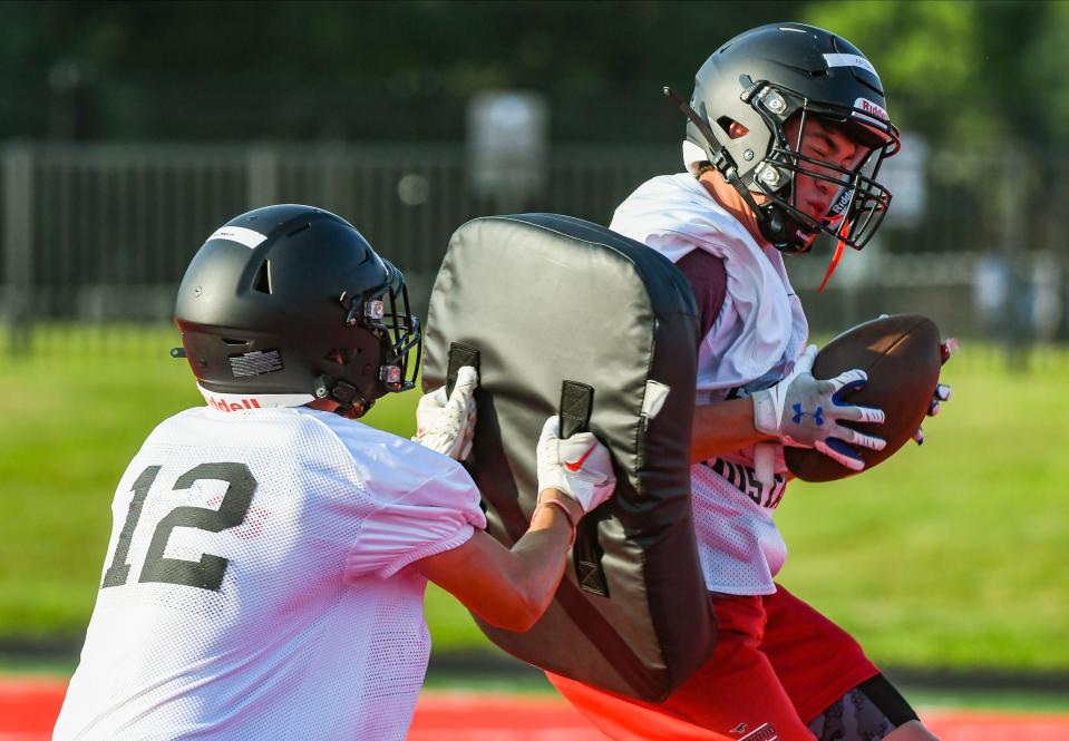 Edgewood’s Christian Couch (right) is hit with a cushioned pad after making a catch during the first day of football practice at Edgewood on Monday, July 31, 2023.
