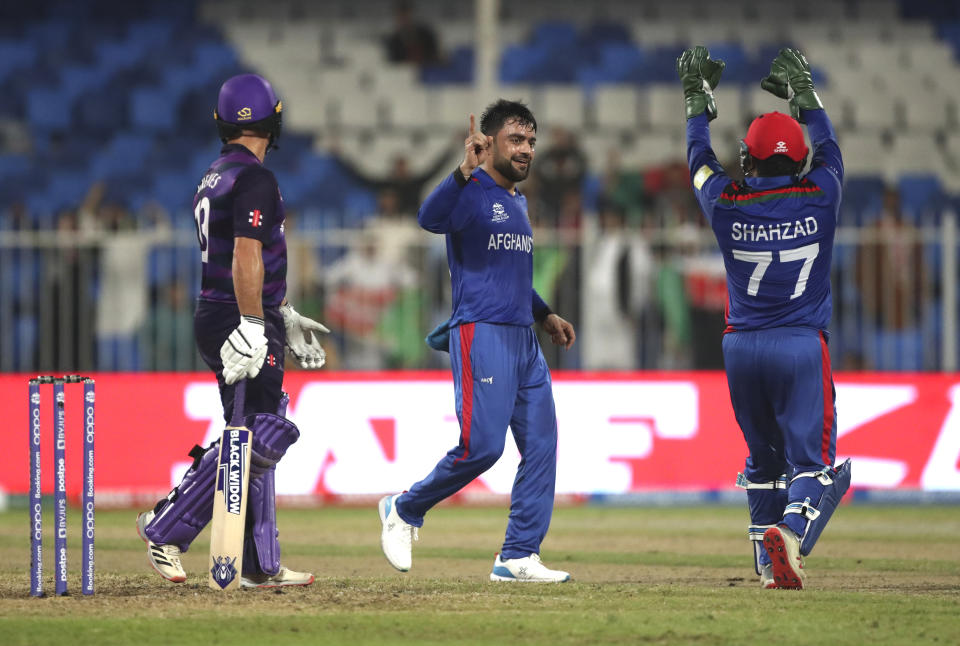 Afghanistan's Rashid Khan, center celebrates the dismissal of Scotland's Chris Greaves, left, during the Cricket Twenty20 World Cup match between Afghanistan and Scotland in Sharjah, UAE, Monday, Oct. 25, 2021. (AP Photo/Aijaz Rahi)