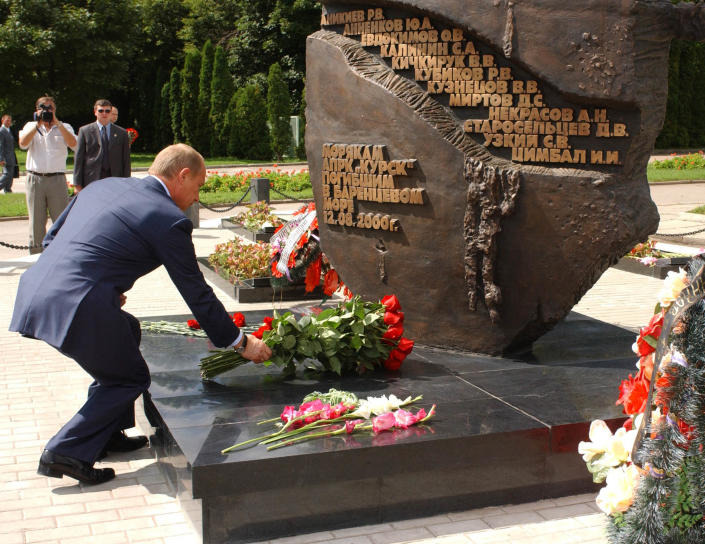 Russian President Vladimir Putin lays flowers at a monument.