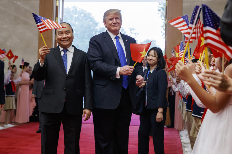 U.S. President Donald Trump and Vietnamese Prime Minister Nguyen Xuan Phuc wave flags before a meeting at the Office of Government Hall, Wednesday, Feb. 27, 2019, in Hanoi. (AP Photo/ Evan Vucci)