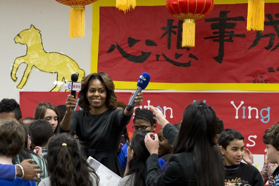 First lady Michelle Obama returns microphones after speaking with a 6th grade class talks about their trip to China, Tuesday, March 4, 2014, at Washington Yu Ying Public Charter School in Washington. In March the first lady is expected to take a trip to China along with her daughters and mother. (AP Photo/Jacquelyn Martin)