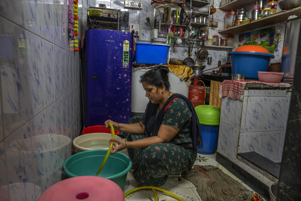 Aarti Sandeep Kawade fills buckets and pans with water for cooking and washing clothes and dishes inside her dwelling in Dharavi, one of Asia's largest slums, in Mumbai, India, Wednesday, May 3, 2023. Municipal water arrives daily from 6 to 9 a.m. "Nothing can be done without water," says the 35-year-old homemaker and mother of two, whose husband works at a local hospital. (AP Photo/Dar Yasin)