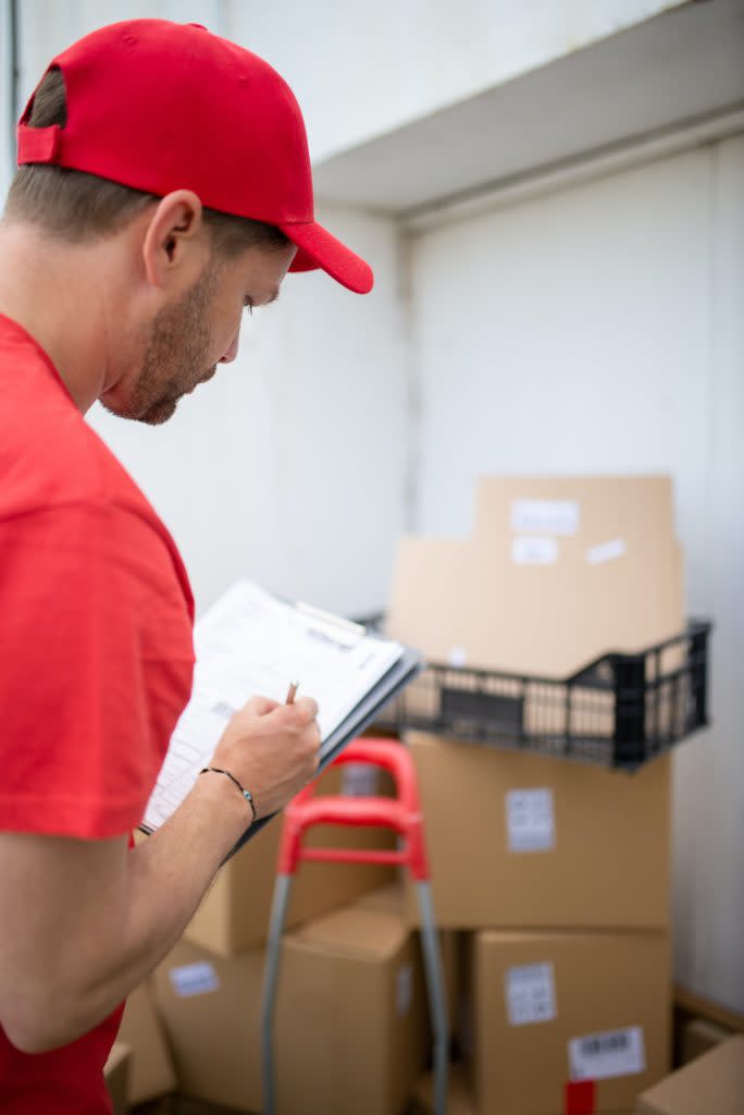 Man reviewing a stack of labeled boxes