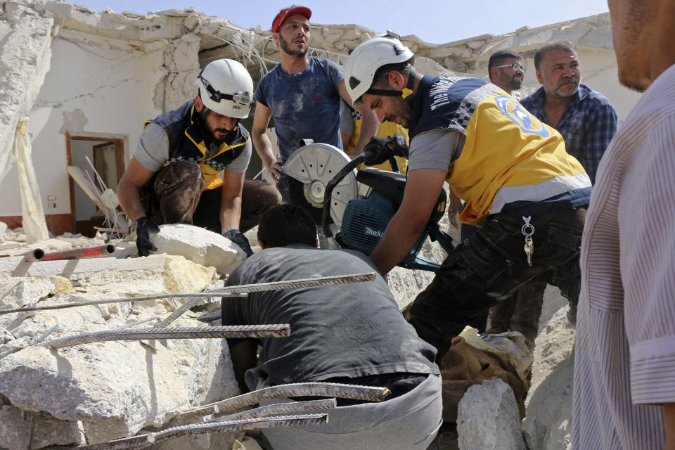 This photo provided by the Syrian Civil Defense White Helmets, which has been authenticated based on its contents and other AP reporting, shows Civil Defense workers searching for victims under the rubble of a destroyed building after an airstrike by Syrian government forces, Maaret al-Numan, a town in south Idlib, Syria, Thursday, May 30, 2019. Rescue workers and activists say at least five, including three from the same family, have been killed in Syria's last rebel stronghold when warplanes targeted the building they live in, leveling it. (Syrian Civil Defense White Helmets via AP)