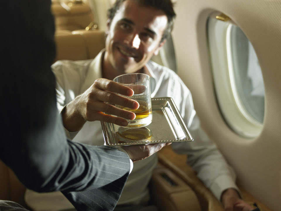 A flight attendant handing a passenger a drink