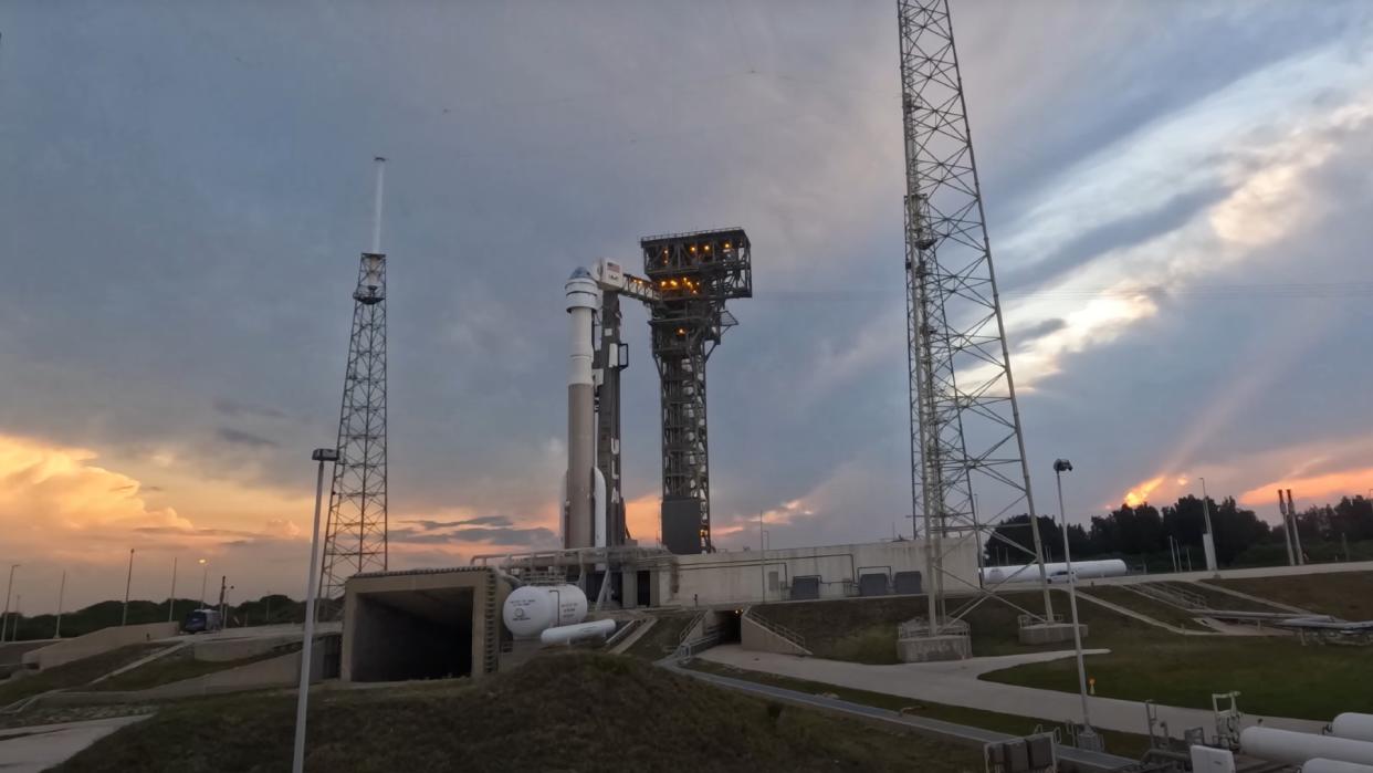  A large white rocket on a launchpad at sunset. 