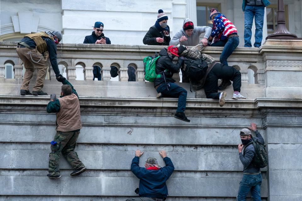 Insurrections loyal to President Donald Trump climb the west wall of the the U.S. Capitol, Jan. 6, 2021, in Washington.