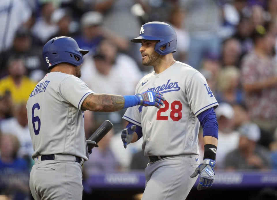 Los Angeles Dodgers' David Peralta, left, congratulates J.D. Martinez as he crosses home plate after hitting a solo home run against Colorado Rockies relief pitcher Brad Hand in the sixth inning of a baseball game Tuesday, June 27, 2023, in Denver. (AP Photo/David Zalubowski)