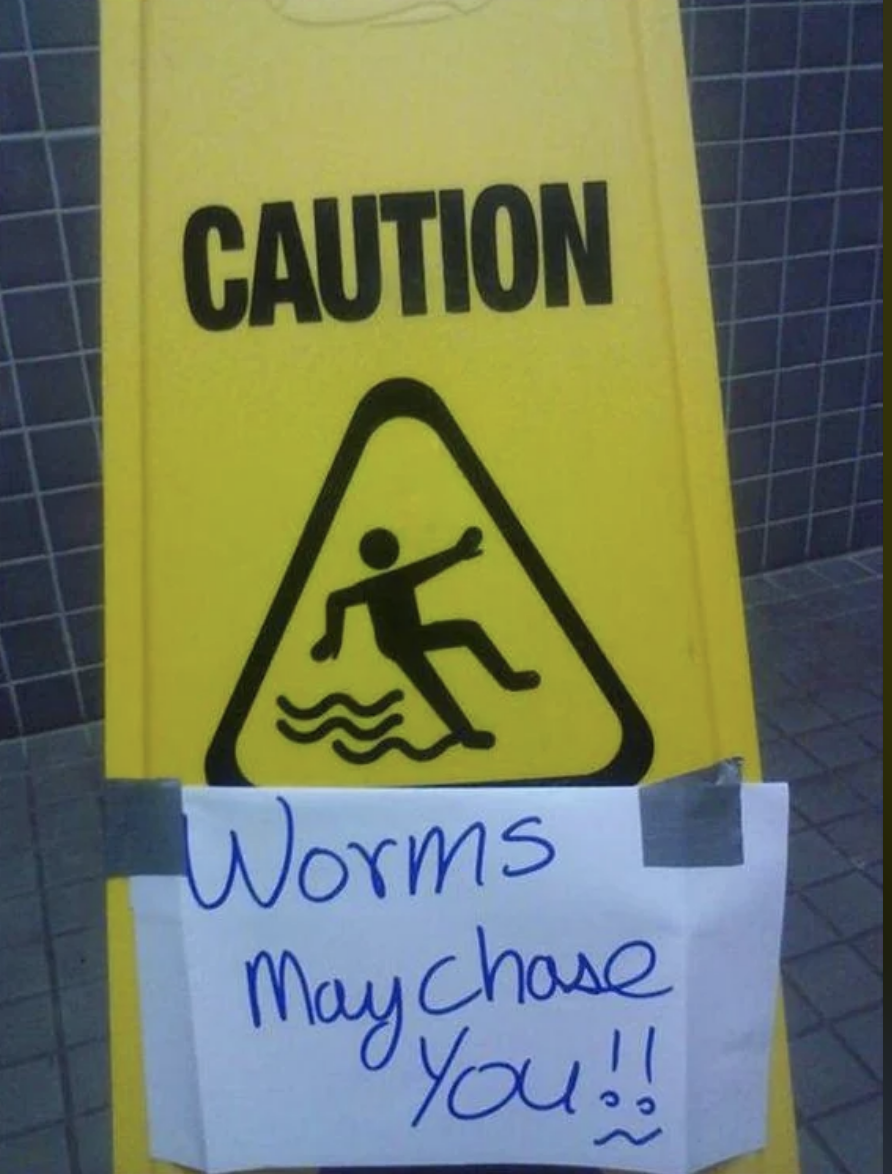 Caution sign with a handwritten note reading "Worms may chase you!!" below a printed warning icon