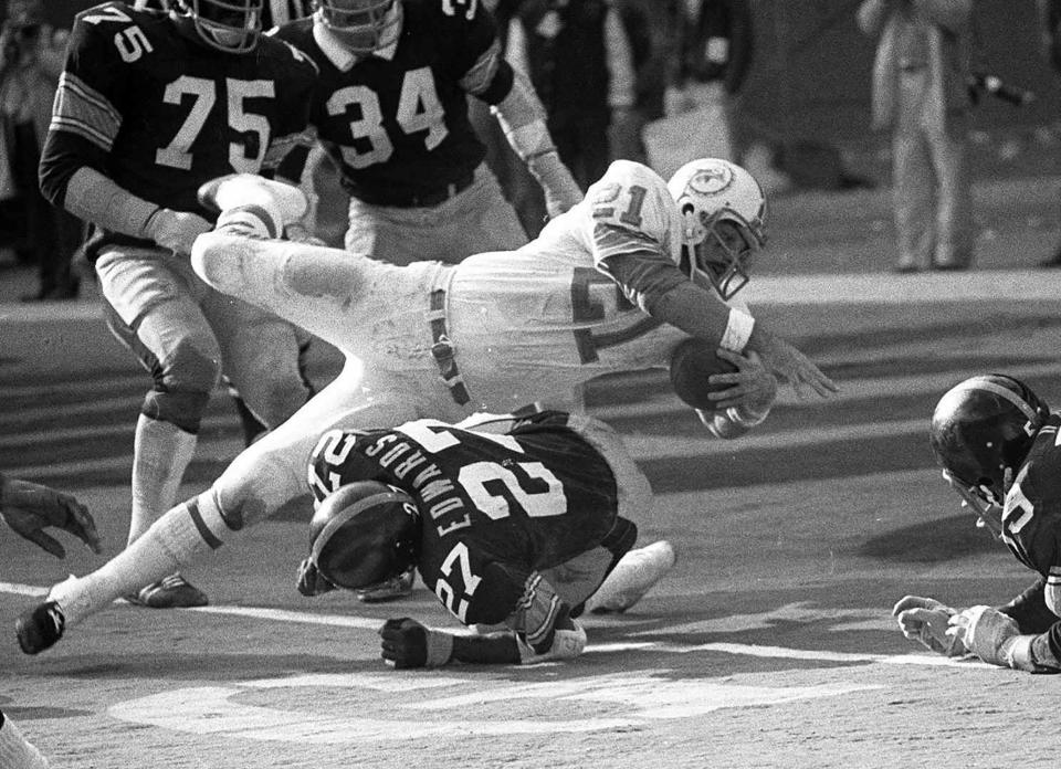 FILE - In this Dec. 31, 1972, file photo, Miami Dolphins Jim Kiick goes headfirst over Pittsburgh Steelers" Glen Edwards as Kiick scores in third quarter of the AFC championship game at Pittsburgh's Three Rivers Stadium. Former running back Kiick, who helped the Dolphins achieve the NFL’s only perfect season in 1972, has died at age 73. In recent years Kiick battled memory issues and lived in an assisted living home, and the team announced his death Saturday, June 20, 2020. (AP Photo, File)